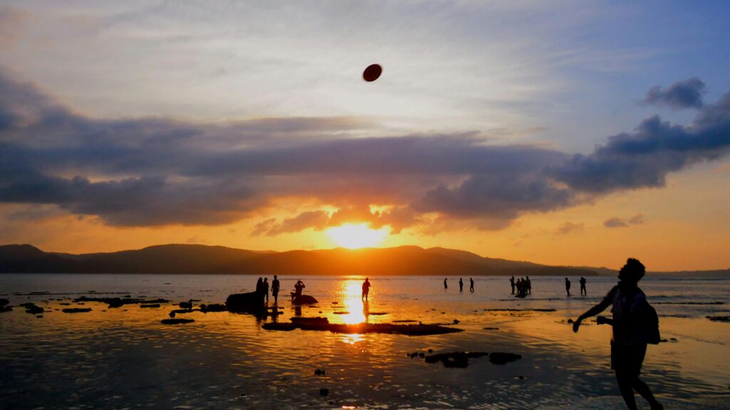 Silhouettes of people enjoying a sunset at a picturesque beach in Port Blair, India.
