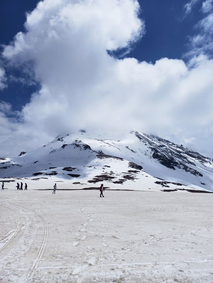 Scenic view of snow-capped peaks under cloudy skies in Rohtang, Himachal Pradesh.