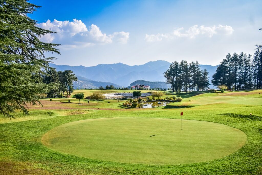 Beautiful golf course with mountains and clear skies, ideal for summer outdoor sports.