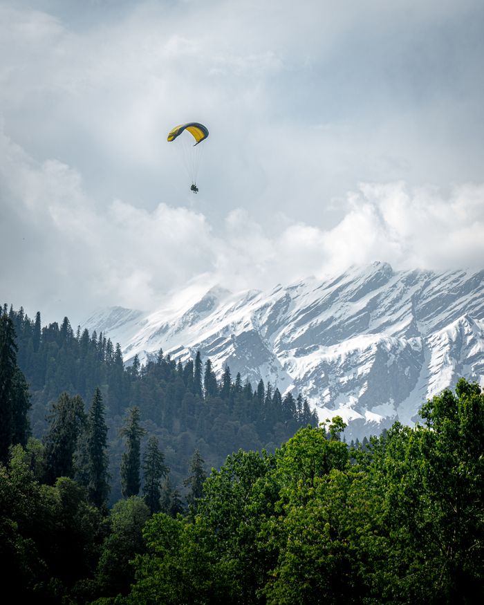 tandem paraglider flying above Solang Valley near Manali Paragliding over Solang Valley during a Solang Valley day trip from Manali