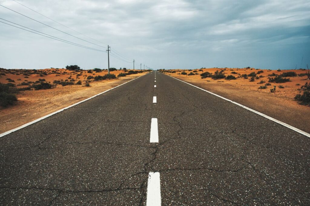 Straight, empty desert road under cloudy sky in Dubai, UAE, highlighting solitude and vastness. Road from Bikaner to Deshnok for the Karni Mata Temple day trip