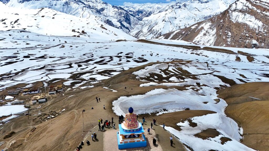 Drone shot of Buddha statue amidst snowcapped mountains in Spiti Valley, HP, India.