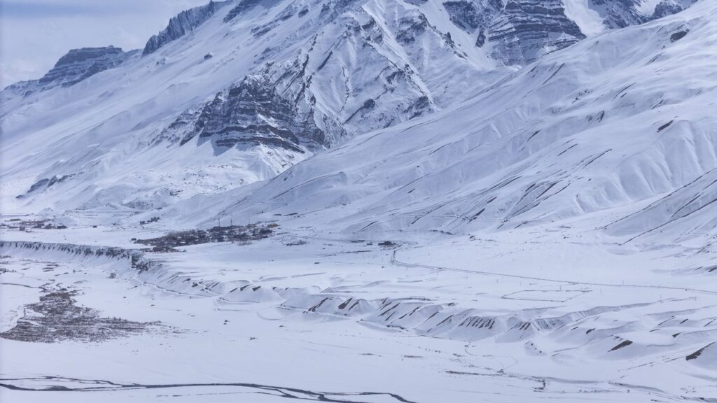 Expansive view of snow-covered Himalayan mountains and valleys during winter, showcasing serene beauty.