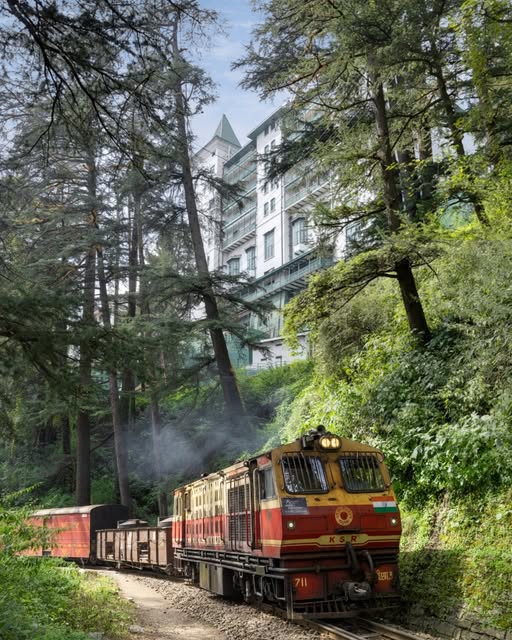 toy train winding through a lush green Himalayan valley near Shimla, small blue and cream train carriages The Kalka-Shimla toy train, a heritage experience among places to visit in Shimla