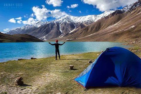 traveller near Chandratal Lake at golden hour, calm reflection of mountains in the water, peaceful and quiet mood Traveller resting near Chandratal Lake during acclimatisation on a Spiti trip